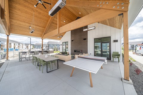 A wooden covered patio with a ping pong table and chairs.