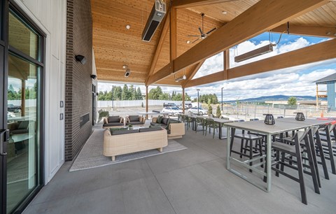 A patio with a table and chairs is covered with a roof.