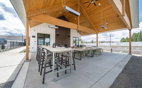 A wooden covered patio with tables and chairs.
