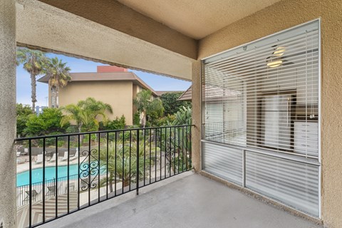 A balcony with a pool and palm trees in the background.