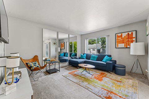 A living room with a blue couch and a colorful rug.