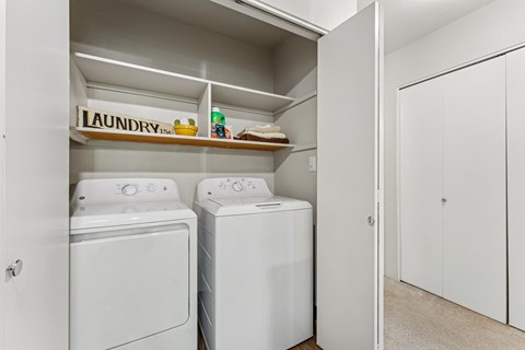 Laundry room with two washing machines and a shelf above them.