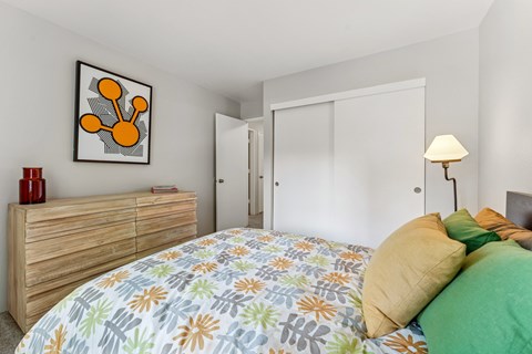 A bedroom with a bed, a dresser, and a painting on the wall.