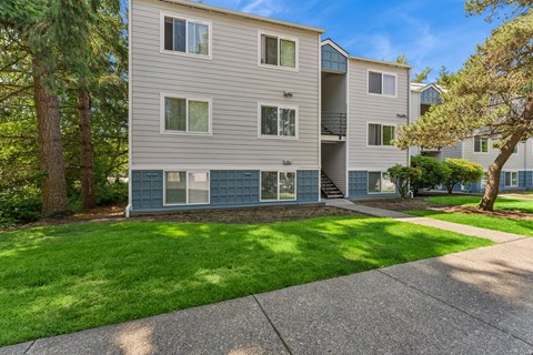 A building with a grey facade and a green lawn in front.