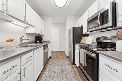 A kitchen with white cabinets and black appliances.