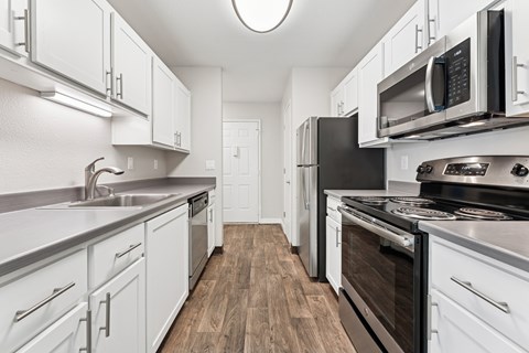 A modern kitchen with white cabinets and stainless steel appliances.