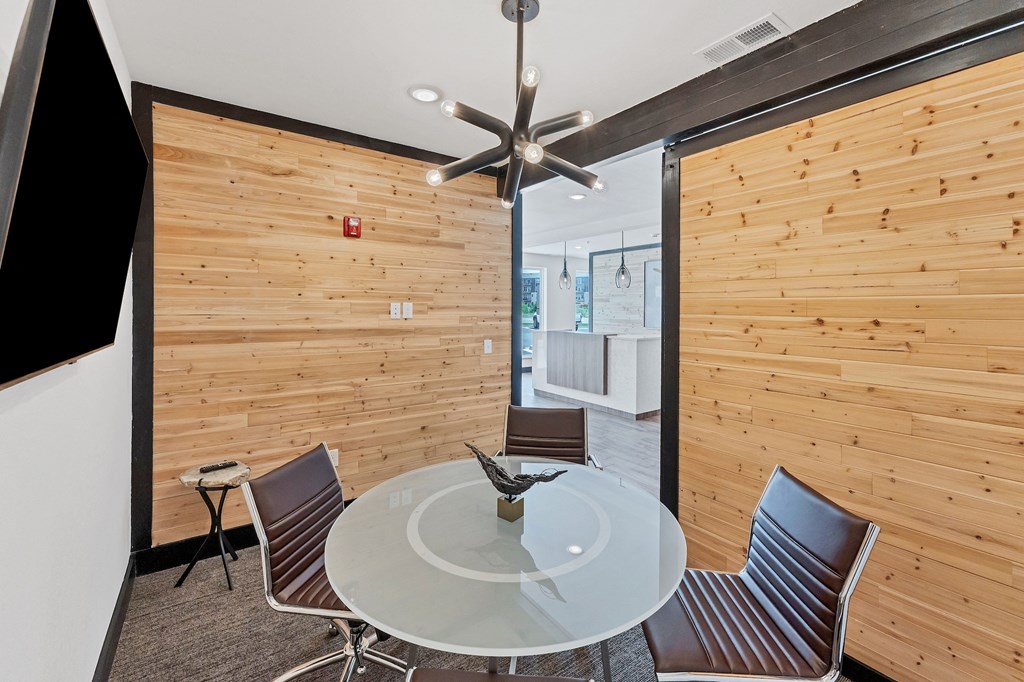 a dining room with a glass table and chairs and a wood wall