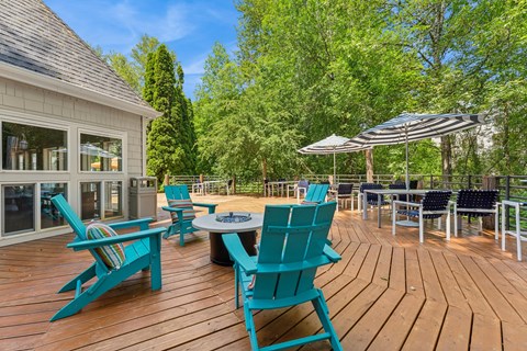 A wooden deck with blue chairs and a table.
