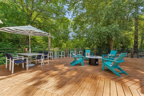 A wooden deck with blue chairs and a table.