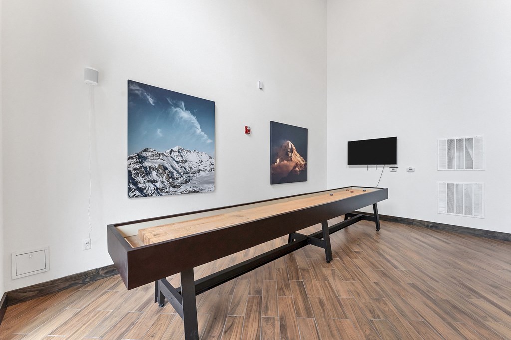 a large white room with a shuffle board and paintings on the wall