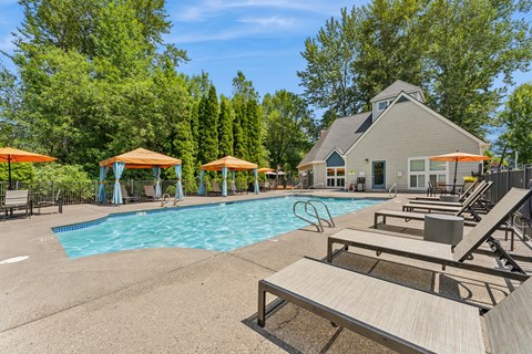 A pool area with sun loungers and a building in the background.