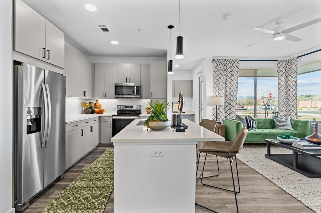 an open kitchen and living room with a stainless steel refrigerator