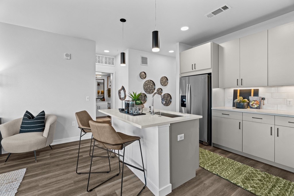 a kitchen with white cabinets and a white island with two stools
