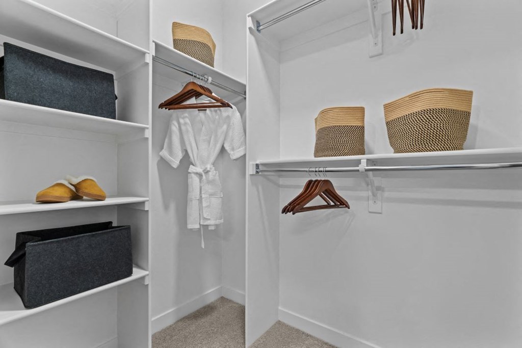 a walk in closet with white walls and shelves and a rack with hats and shoes
