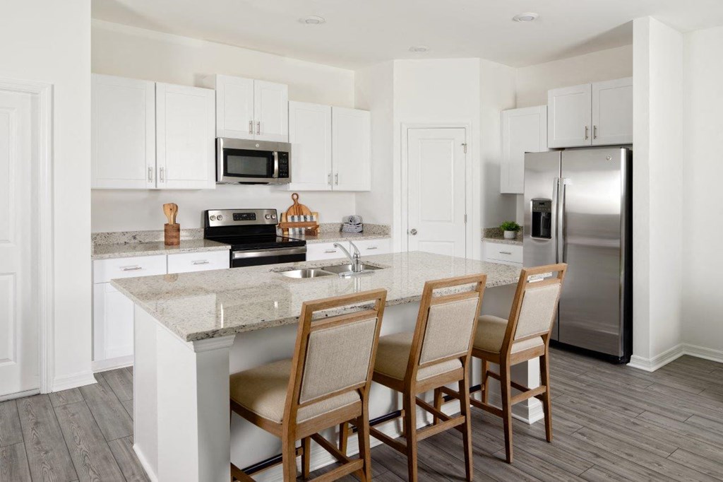 a kitchen with white cabinets and a marble counter top