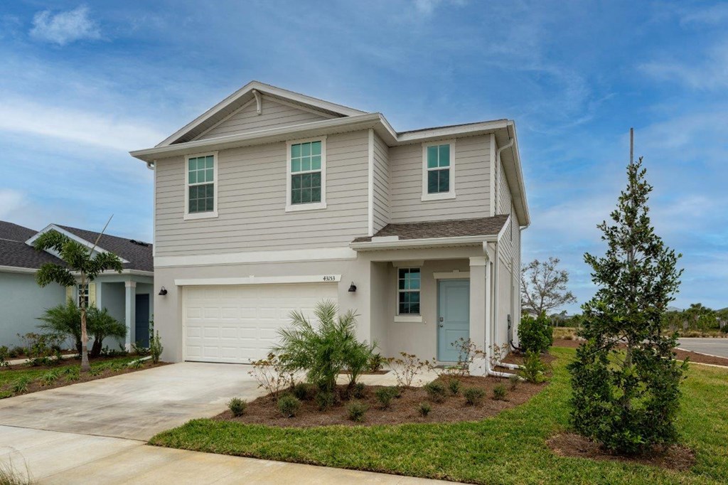 a beige house with green shutters and a driveway