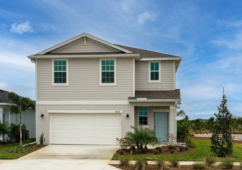 a tan house with a garage door and a driveway