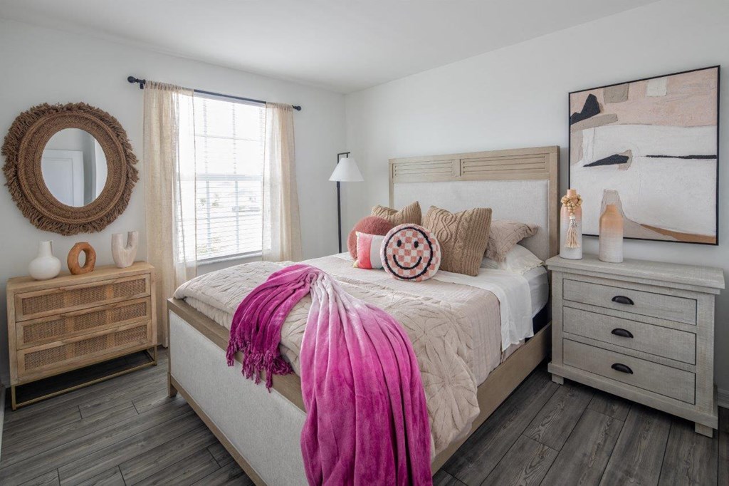 a bedroom with a bed with a pink blanket and pillows