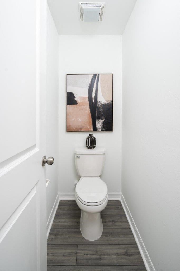 a bathroom with a white toilet and a painting on the wall