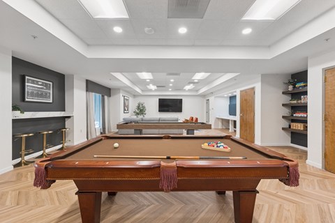 A pool table is in the middle of a room with a fireplace and a TV.