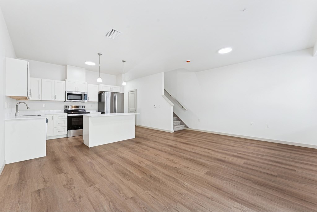 A kitchen with white cabinets and a wooden floor.