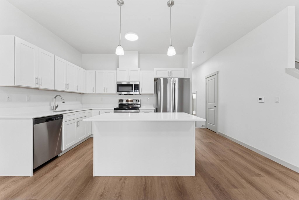 A modern kitchen with a white island and stainless steel appliances.