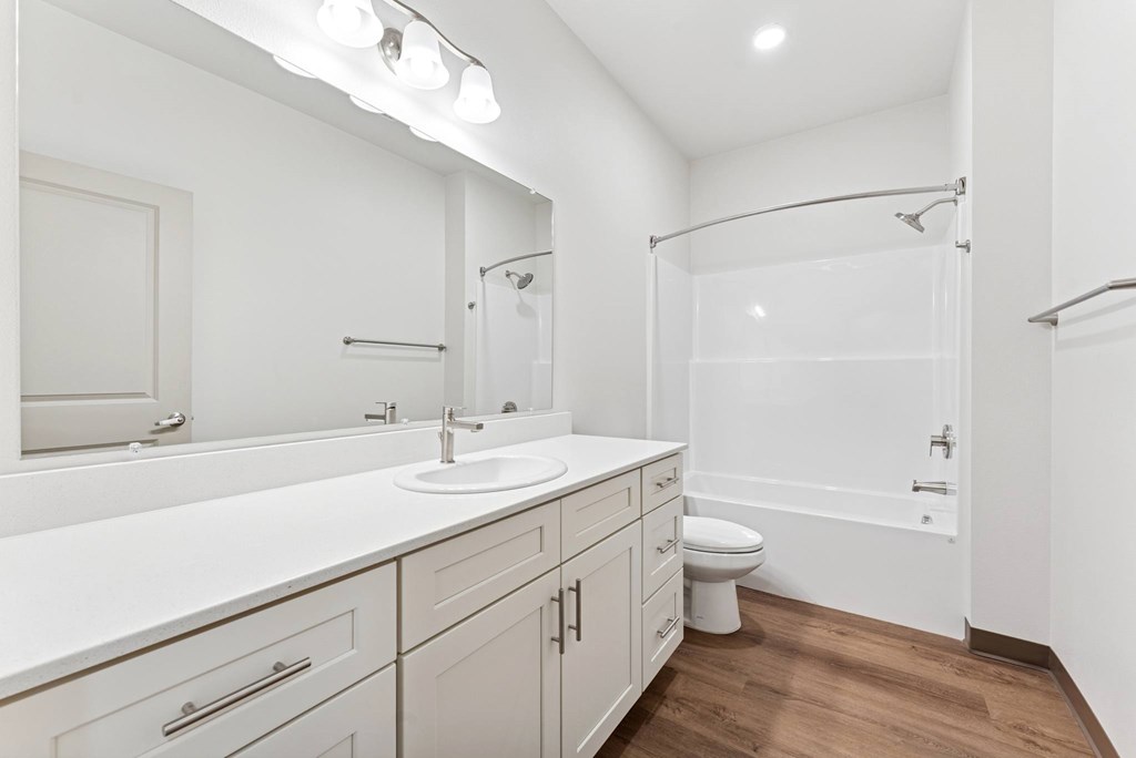 A white bathroom with a toilet, sink, and shower.