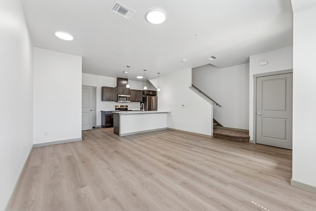 A spacious kitchen with a bar area and a staircase in the background.