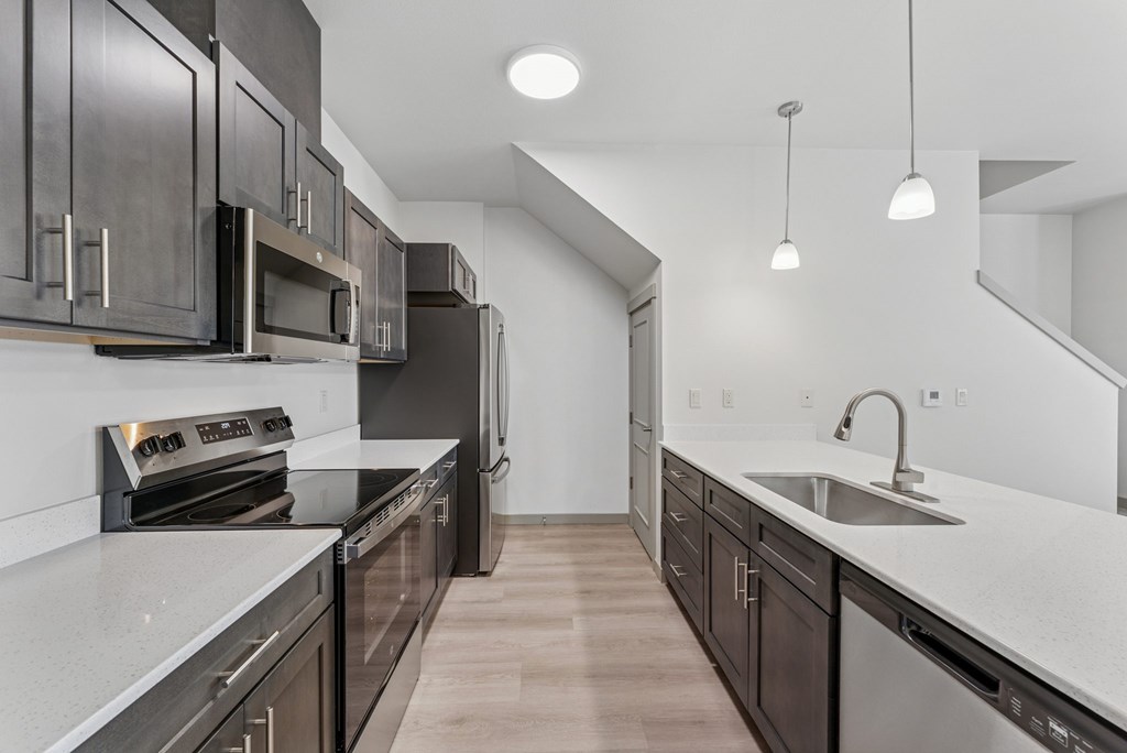 A modern kitchen with dark wood cabinets and stainless steel appliances.