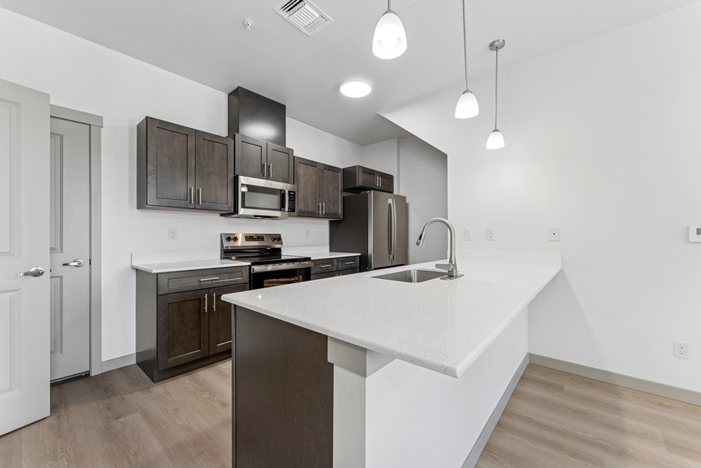 A modern kitchen with a white countertop and dark brown cabinets.