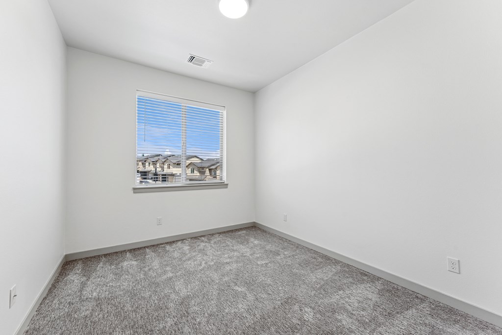 A room with a carpeted floor and a window with blinds.