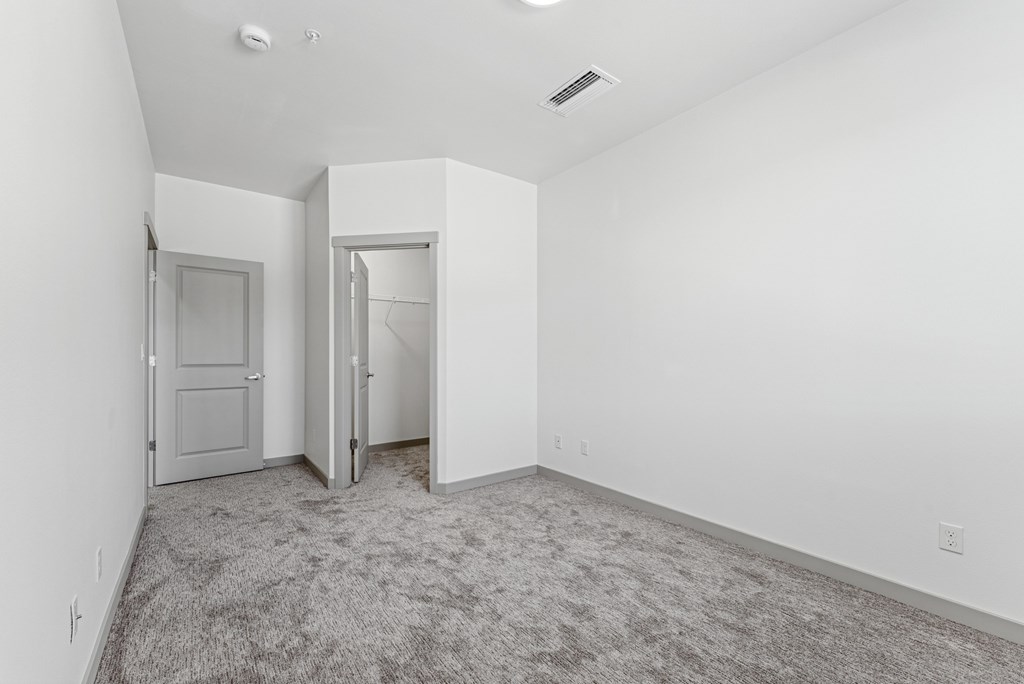 A room with a carpeted floor and two doors.