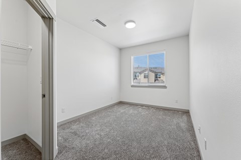 A room with a carpeted floor and a window showing a building outside.