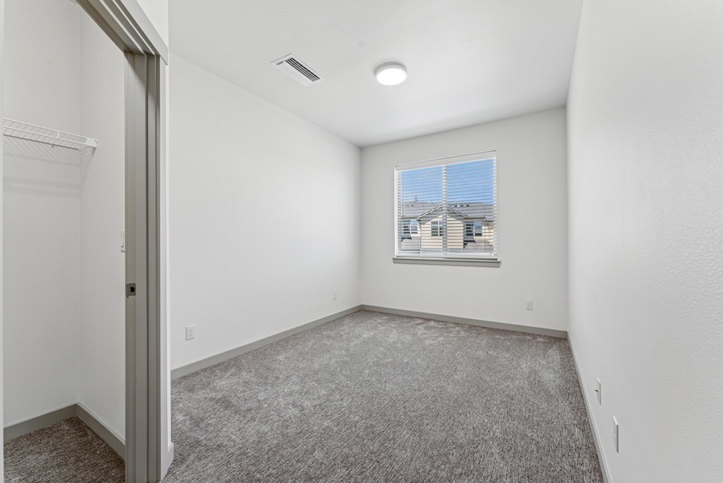 A room with a carpeted floor and a window showing a building outside.