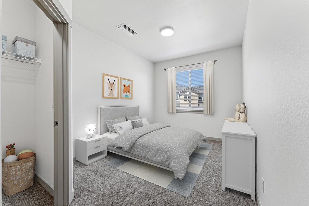 A bedroom with a bed, nightstand, and a window with a view of a building outside.