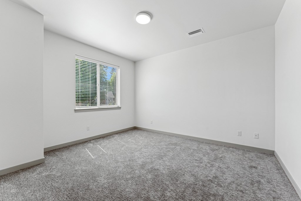 A room with a window and carpeted floor.