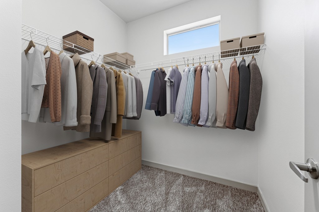 A row of clothes hanging on a rack in a room.