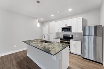 A kitchen with a granite countertop and stainless steel appliances.
