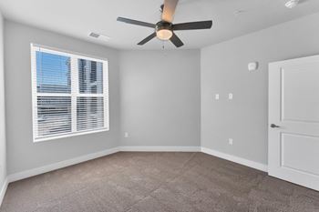 A room with a ceiling fan and a window with blinds.
