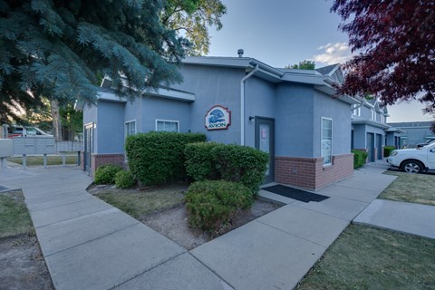 the front of a blue building with a sidewalk and trees