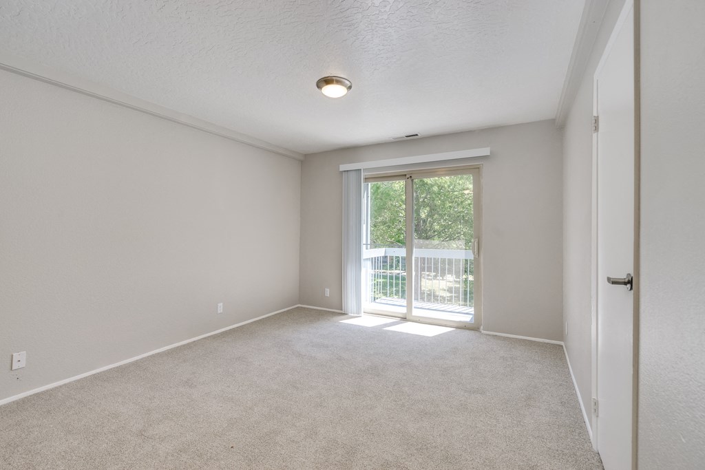 an empty living room with a door to a balcony