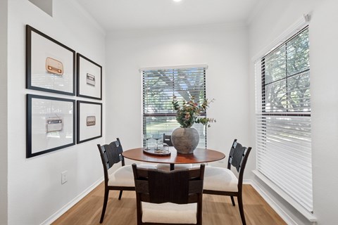A dining room with a table and chairs and pictures on the wall.