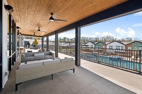 A patio with a couch and a pool in the background.