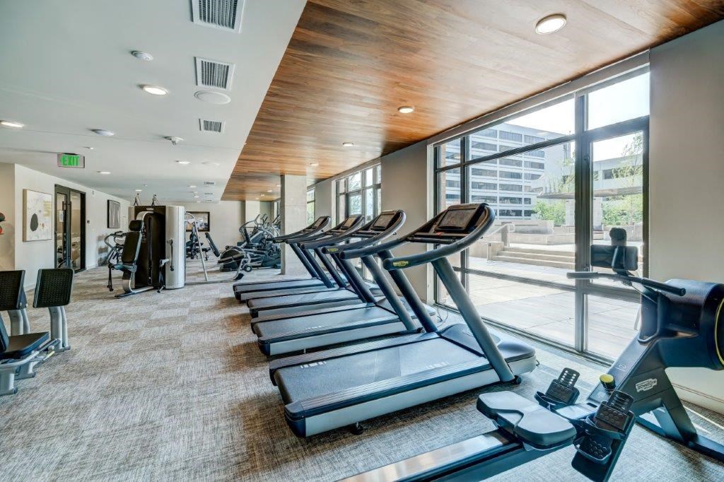a gym with cardio machines and a large window