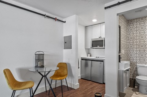 a kitchen with a small table and chairs and a bathroom with a sink