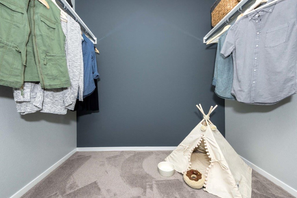 a childrens bedroom with a teepee tent and clothes hanging on the wall