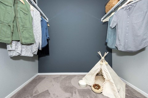 a childrens bedroom with a teepee tent and clothes hanging on the wall