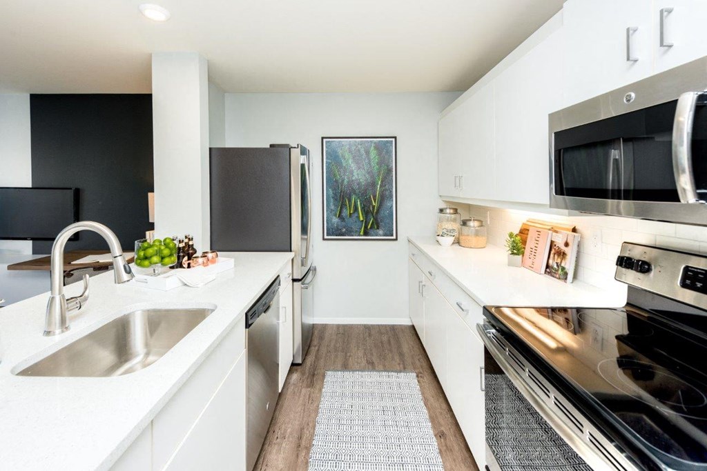 a white kitchen with stainless steel appliances and a sink