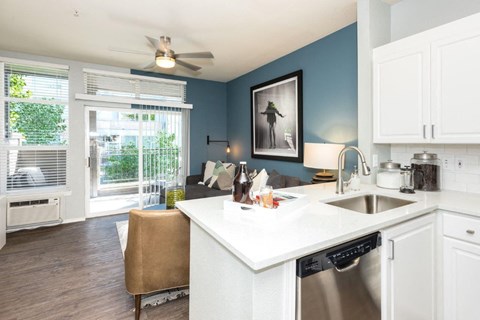 a kitchen and living room with a sink and a ceiling fan