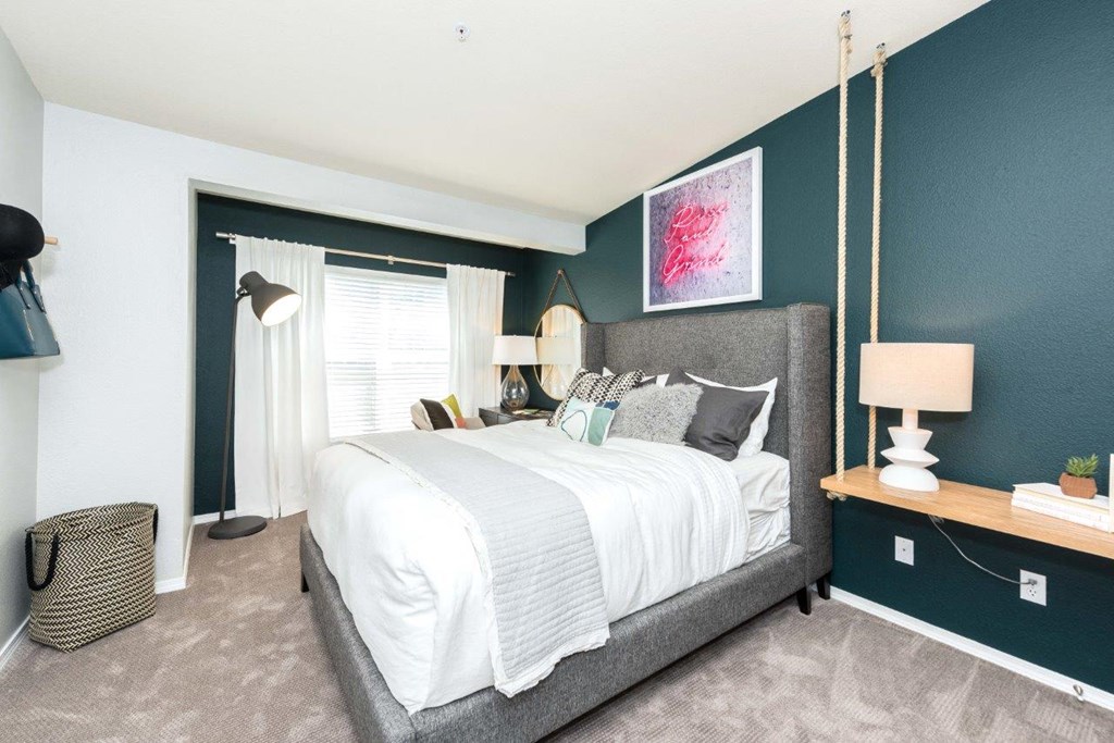 a bedroom with a bed and a blue wall and a window